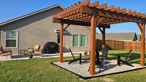 A backyard with a wooden pergola, outdoor furniture, and a barbecue grill. - Cute Brand New Home in McKinney (McKinney)