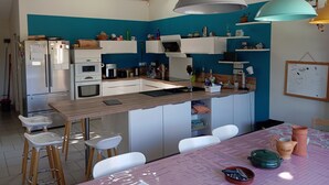A modern kitchen with a central island, white cabinets, and a blue accent wall. - House and pool (Fontenilles)