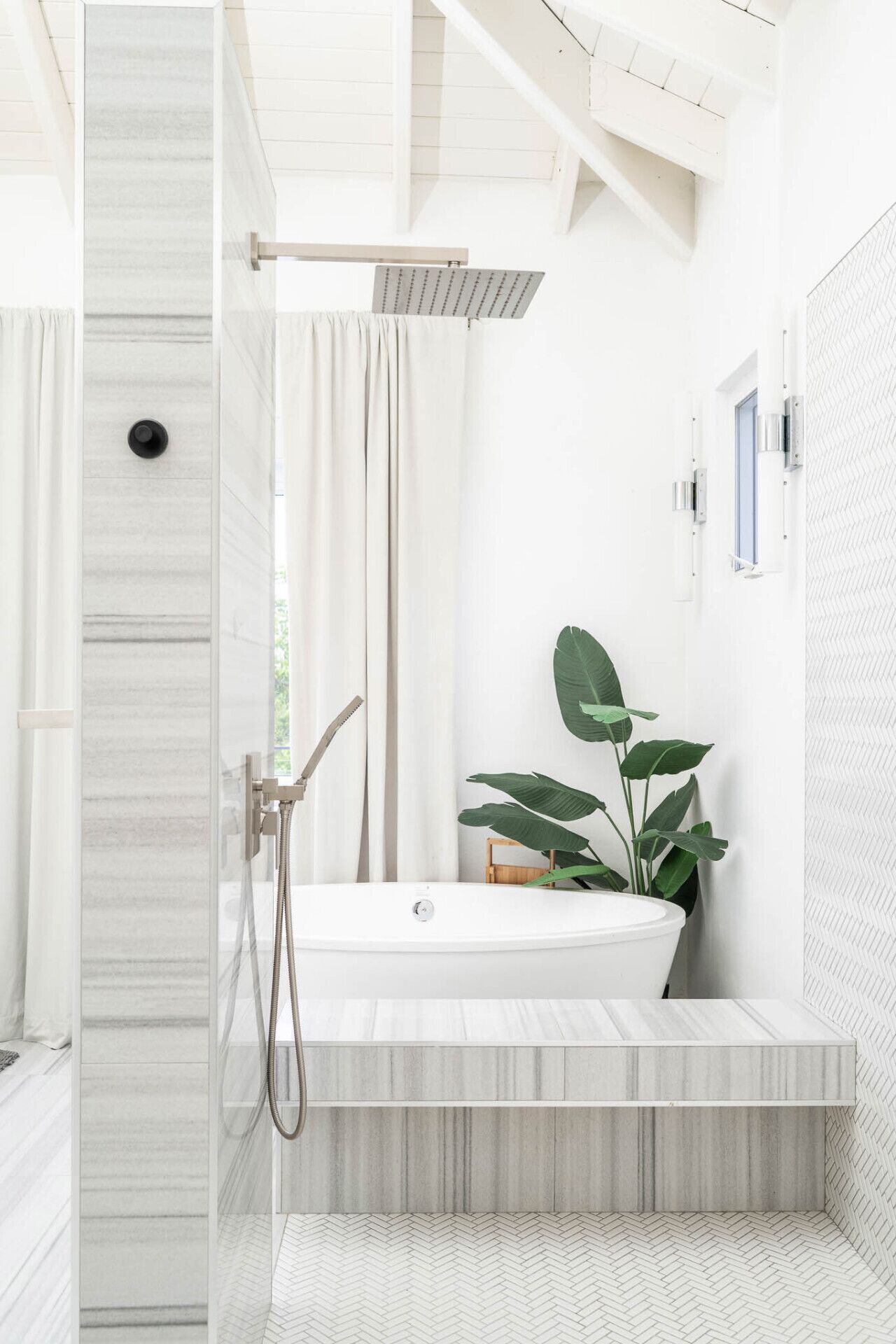 A modern bathroom with a freestanding bathtub, a showerhead, and a potted plant.