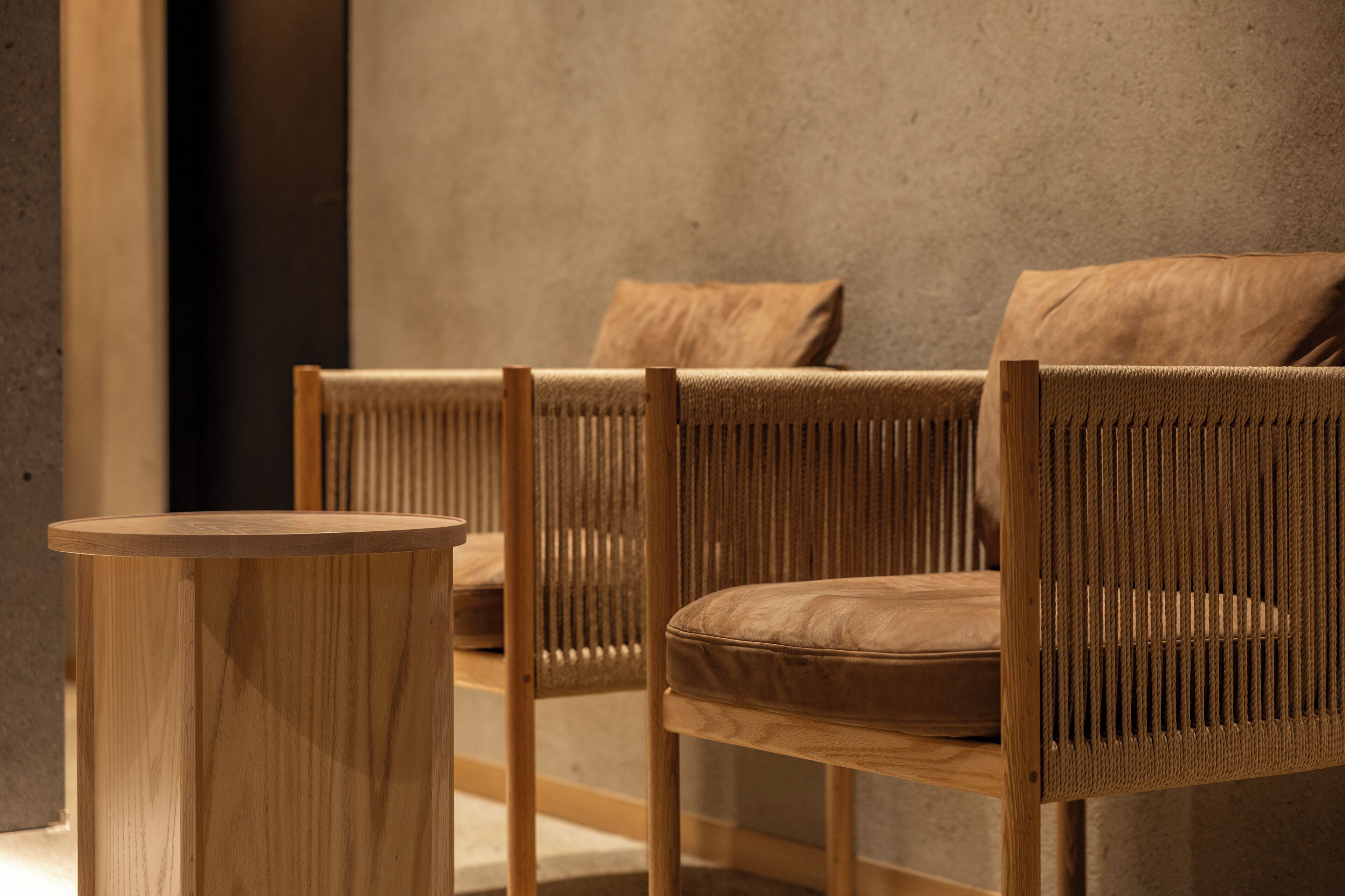 A room with two wicker chairs and a wooden side table.
