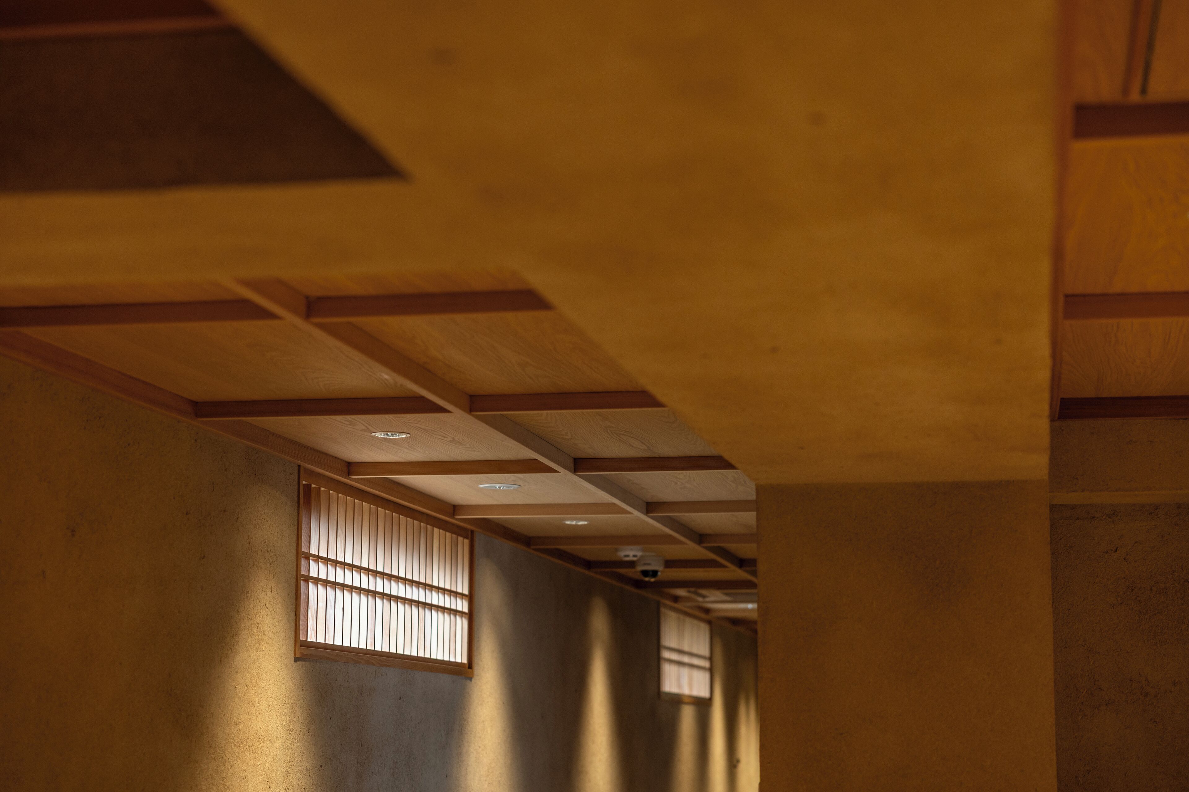 A hallway with wooden beams and a ceiling with recessed lighting.