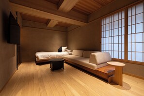 A modern interior with a sofa, a small round table, and a TV mounted on the wall. - soyo-ne kyoto sanjo (Kyoto)