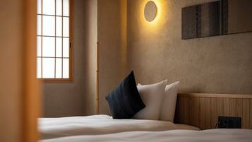 Ein Hotelzimmer mit Bett, Fenster, Wandlampe und Steckdose.