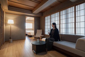 A room with a sofa, a chair, a lamp, a small table, and a bed in the background. - soyo-ne kyoto sanjo (Kyoto)