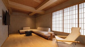 A modern interior with a wooden ceiling, a sofa, a chair, and a large window with grid panes.