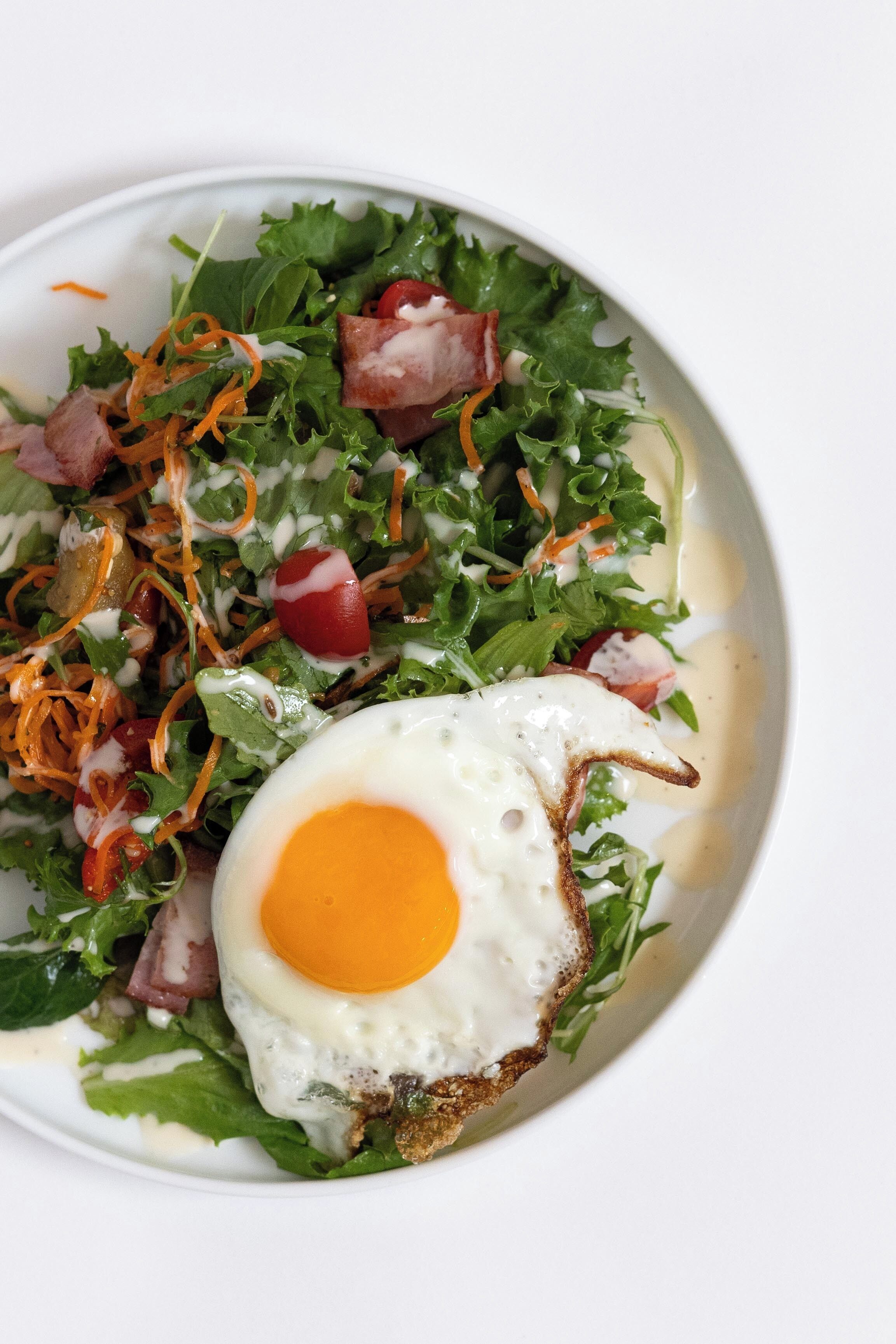 Un plato con ensalada y un huevo frito.