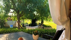 Ein Sitzbereich im Freien mit Tisch, Stühlen, einer Hängematte und Blick auf eine grüne Landschaft.