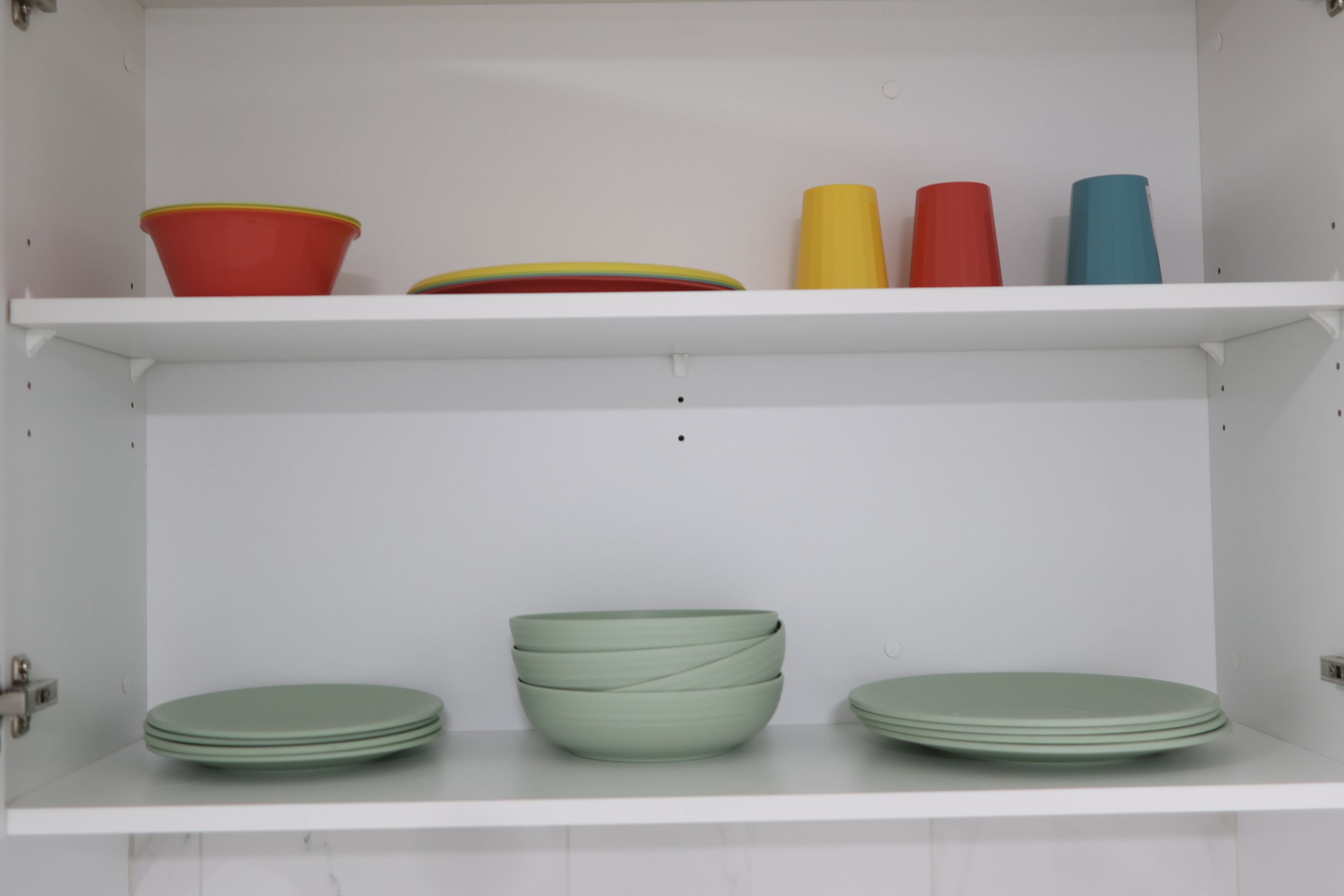 A kitchen with white cabinets and shelves.