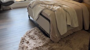 Una camera da letto moderna con un letto grande, una sedia, una finestra con tende e un punto luce a parete.