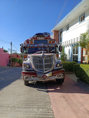 Un camión colorido estacionado frente a un edificio con fachada blanca y detalles azules.