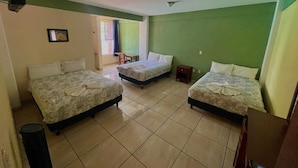 Une chambre avec trois lits, une petite table et une chaise.