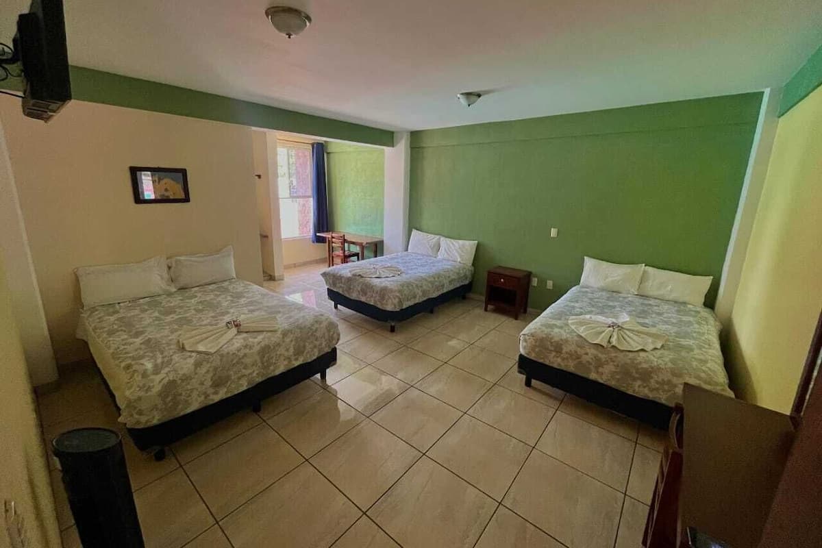 Ein Zimmer mit drei Betten, einem kleinen Tisch und einem Stuhl.