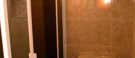 Une salle de bain comprenant des toilettes, un espace douche et un mur carrelé agrémenté d’une bordure décorative.