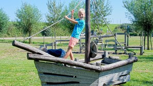 Un bambino gioca su una struttura a forma di barca di legno in un parco.