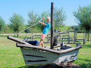 Un niño juega en una estructura de barco de madera en un parque.