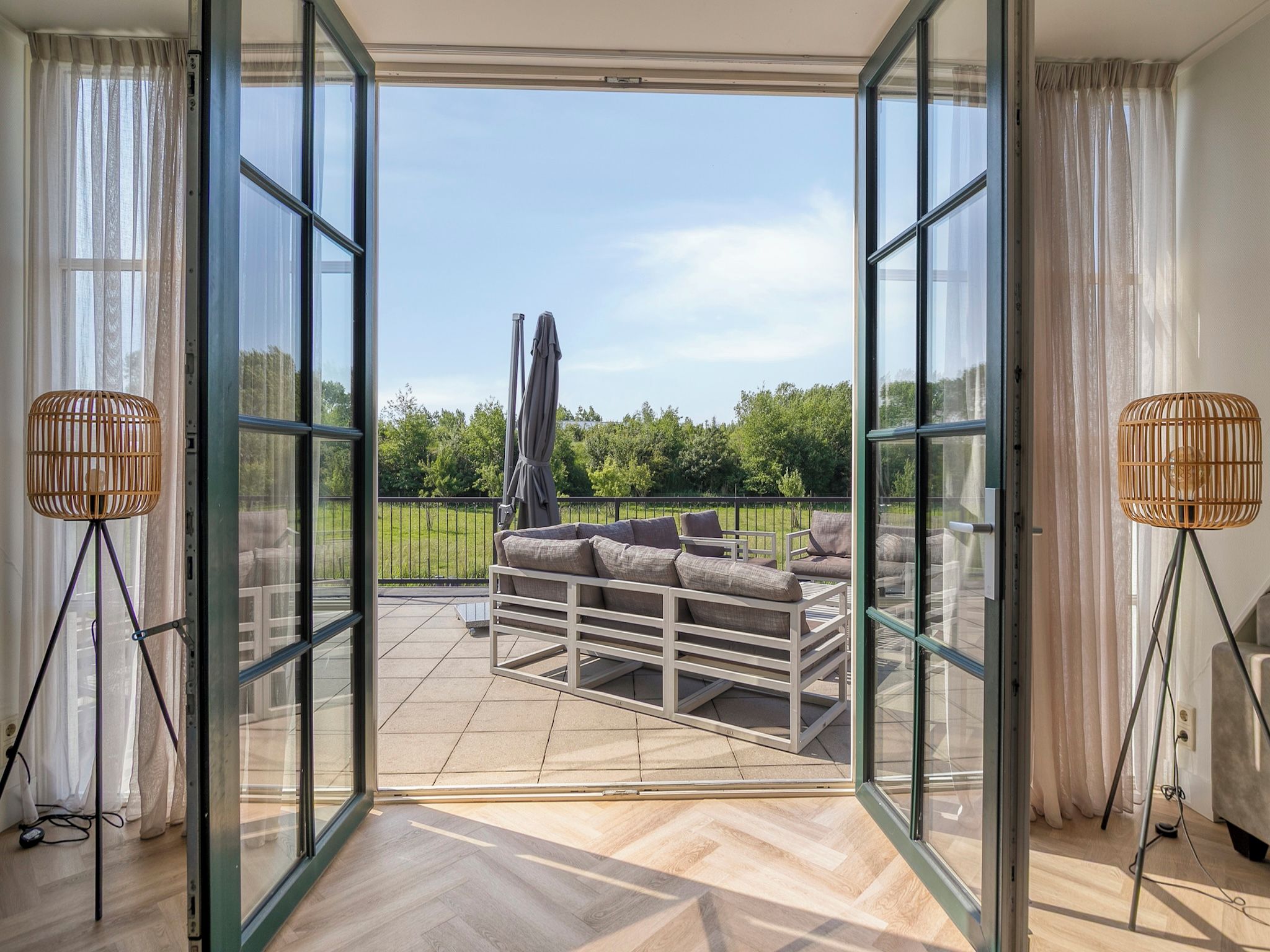 A modern room with a glass door leading to an outdoor patio area with a sofa and umbrella.