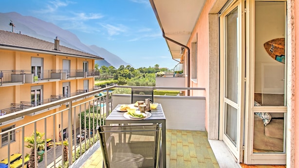 A balcony with a table set for breakfast, a sliding glass door, and a view of a mountain.