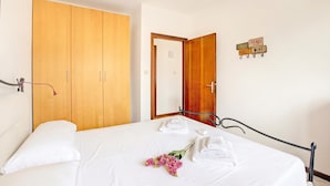 A bedroom with a bed, wooden wardrobe, and a wall sign.