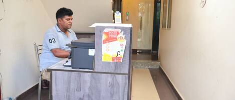A man sitting at a desk with a computer and a poster advertising a promotion.