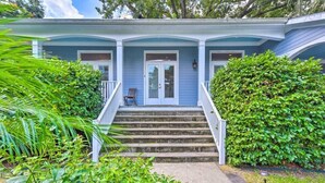 Ein zweistöckiges Haus mit Veranda, Steinstufen und einem gepflegten Garten.