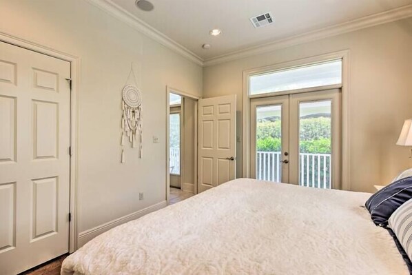 Un dormitorio con una cama grande, dos puertas y un atrapasueños en la pared.
