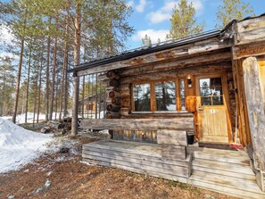 A log cabin with a wooden porch, large windows, and a door with a number plaque. - Kelorakka 9 by Interhome (Kittilä)