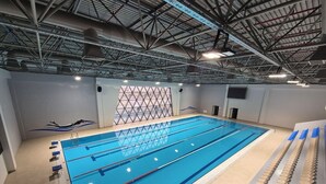 An indoor swimming pool with lanes, starting blocks, and a ceiling with visible structural beams. - Arena Hotel Goranboy (Goranboy)