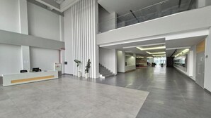 Un vestíbulo amplio y moderno con una recepción, una escalera y un entrepiso.