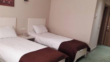 Habitación de hotel con dos camas, alfombra verde, teléfono en la pared y una puerta.