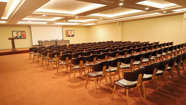 A conference room with rows of chairs, a podium, and two portraits on the wall. - Arena Hotel Goranboy (Goranboy)