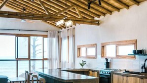 Une cuisine moderne dotée d’un grand îlot central, d’un plafond en bois et de grandes fenêtres.