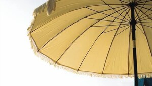 Une scène de plage avec un parasol jaune, des chaises longues et une plage de sable.