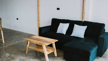 Une pièce avec un canapé vert foncé, deux coussins à rayures et une table en bois.