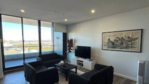 Una sala de estar moderna con un televisor grande, asientos cómodos y vistas de la ciudad.