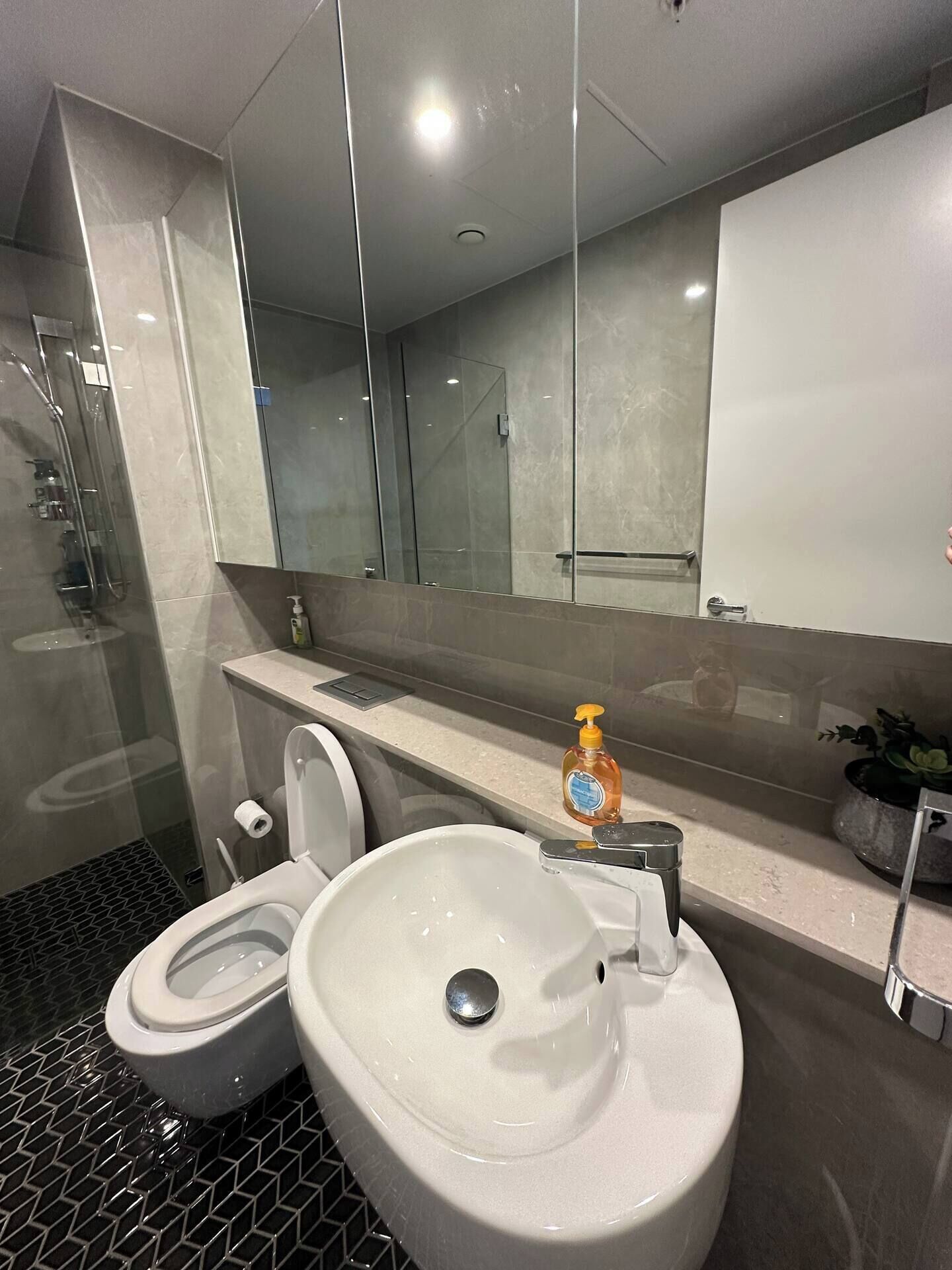 Un baño moderno con cabina de ducha de vidrio, inodoro y lavamanos.