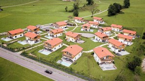 A residential area with multiple houses, each with a red roof and white walls, arranged in a grid pattern with a road in the foreground. - Chalet 19 with balcony and mountain view (Inzell)