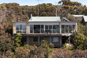 A two-story building with large windows, a balcony, and a metal roof.