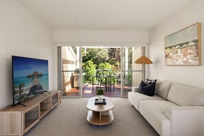 A living room with a sofa, coffee table, TV, and artwork. - Bella Haven | Panoramic Coastal Views | Sleeps 10 (Fairhaven)