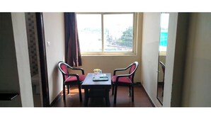 Quarto com uma mesa, duas cadeiras, uma janela com vista e uma porta para outro espaço.