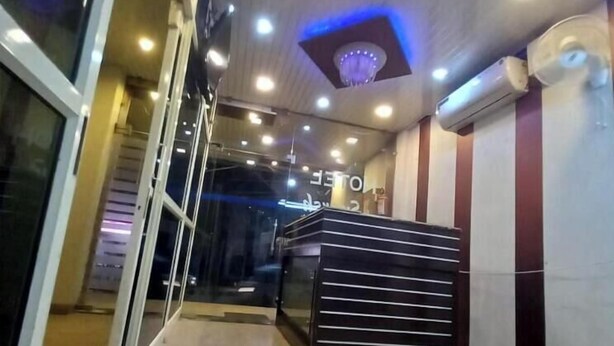 Um saguão de hotel com uma mesa de recepção, uma escada e um teto com iluminação embutida.