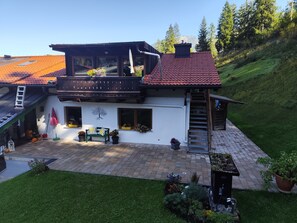 A two-story house with a balcony, a wooden deck, and a garden.