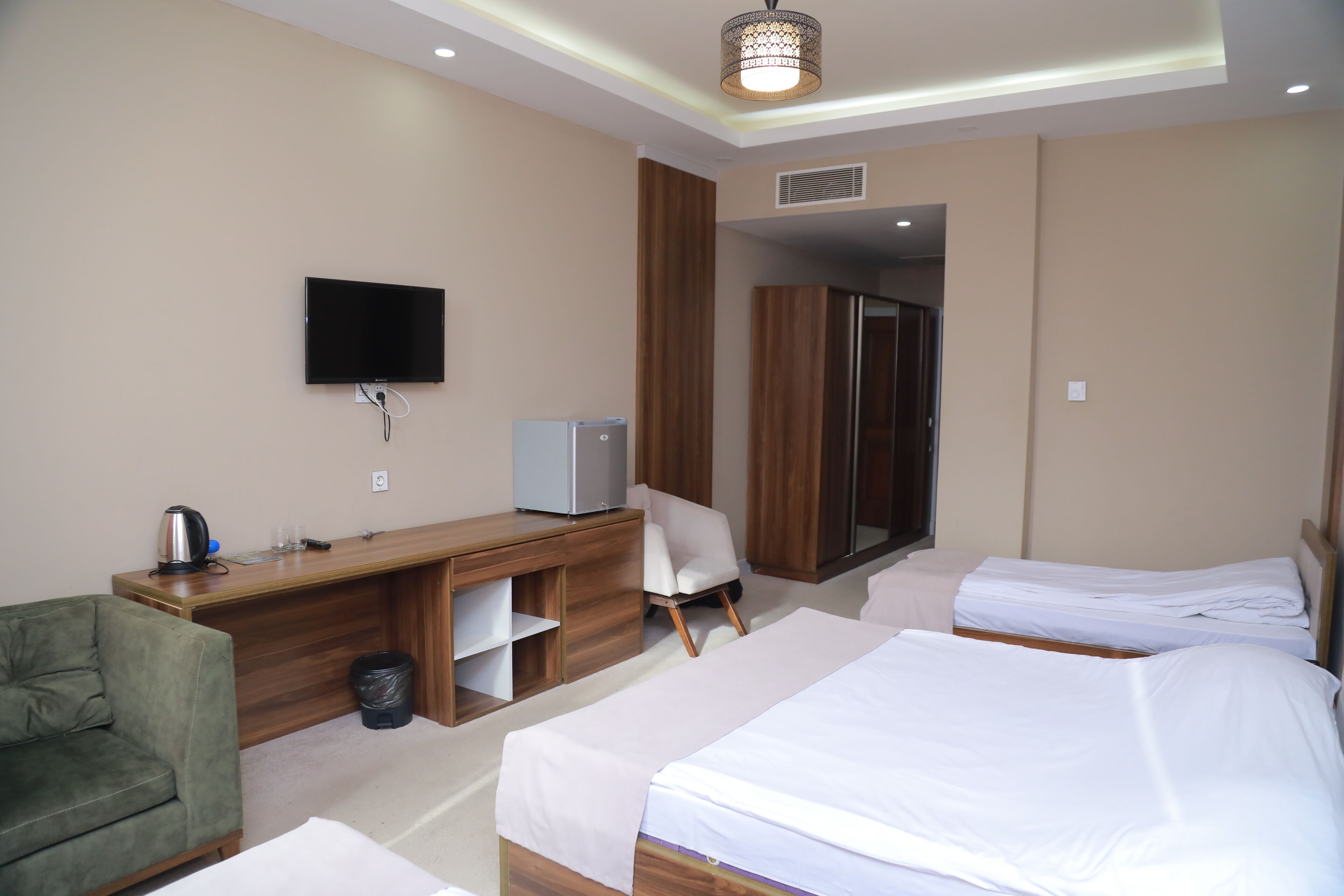 Una habitación de hotel con cama, escritorio, silla, televisor y armario.