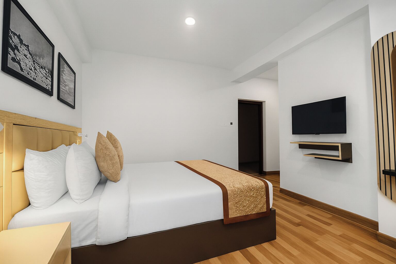 Una habitación de hotel moderna con una cama grande, un televisor de pantalla plana montado en la pared y suelo de madera.