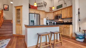 A modern kitchen with wooden cabinets, stainless steel appliances, and a central island with stools.