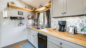 Een moderne keuken met houten aanrecht, vaatwasser, koffiezetapparaat en broodrooster.
