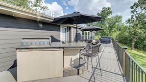 An outdoor deck with a grill, bar area, and outdoor seating. - Outdoor Kitchen + Hot Tub: Table Rock Lake House (Golden)