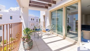 A balcony with two chairs, a potted plant, and a sliding glass door leading to a living area. - Moraira Club 210 - Grupo Turis - Moraira, Costa Blanca (Moraira)