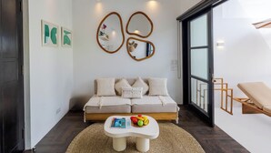 A modern living room with a sofa, coffee table, and artwork. - Villa Gael by Pertama Stay (Seminyak)