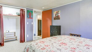 Een slaapkamer met een bloemenbedekker, een garderobe en een dressoir.