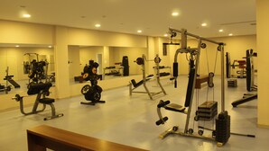 A gym with various exercise equipment, mirrors, and a wooden bench. - Arena Hotel Yardimli (Yardimli)